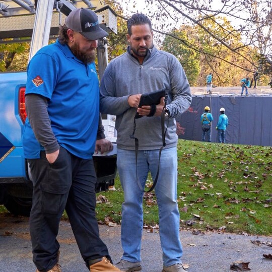 Hands holding cell phone viewing GAF roofing contractor resources