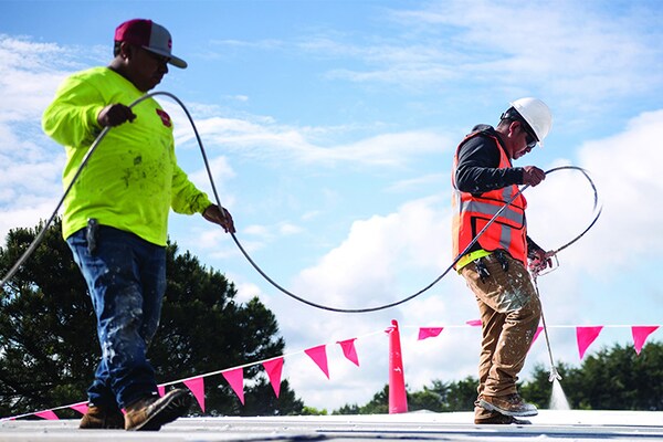 Commercial roofing contractors spraying roof coating products