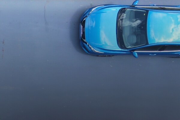 Blue car driving on street with new GAF Roads roadway maintenance