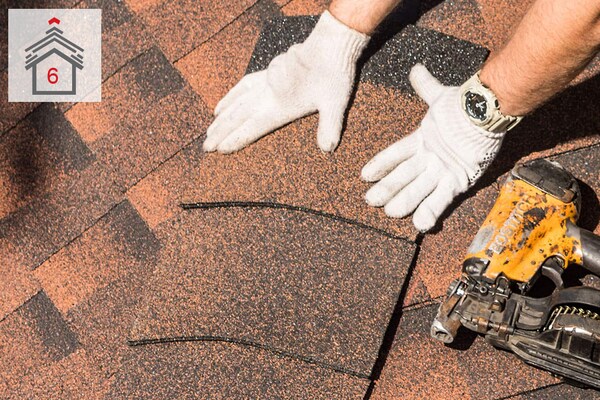 Hands of contractor installing ridge cap shingles