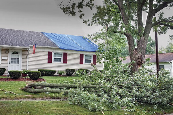 Home with blue tarp on roof after storm damage