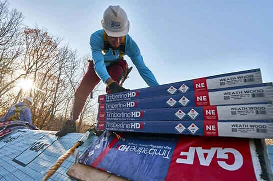 Roofer stacking bundles of Timberline HDZ shingles on a roof