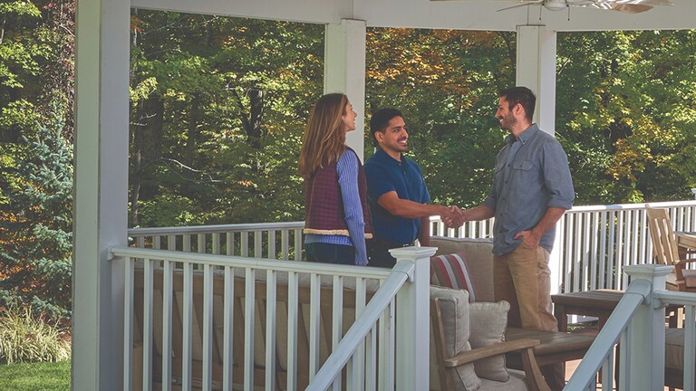 Roofer shaking homeowners hand on porch